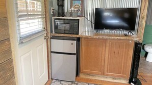 Eine kompakte Küche mit Kühlschrank, Mikrowelle, Kaffeemaschine und Fernseher.