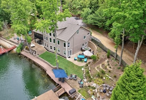 Relax in a serene environment surrounded by trees and shrubs, with a dock and covered outdoor seating area perfect for social gatherings.