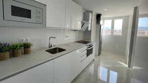 A modern kitchen with white cabinets, a built-in oven, and a stainless steel sink.