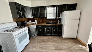 Una cocina compacta con armarios oscuros, una estufa blanca y un refrigerador.