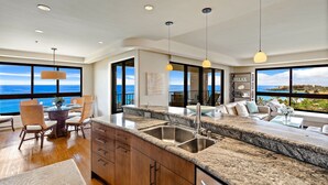Una cocina moderna con una isla grande, encimeras de granito y vista al océano.