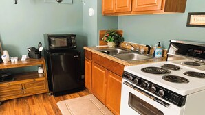 Une cuisine compacte équipée d’un four à micro-ondes, d’un réfrigérateur, d’une cuisinière et d’armoires en bois.