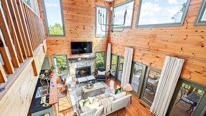 Un salón amplio con chimenea, asientos y ventanas grandes.