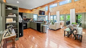 Una cocina amplia con suelo de madera, un comedor con mesa y bancos, y una sala de estar con sofá.
