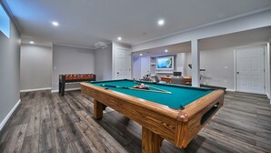A spacious room with a pool table, a foosball table, and a television.