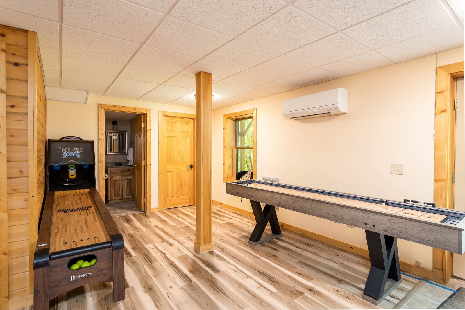Una habitación con mesa de billar, máquina de billar y suelo de madera.