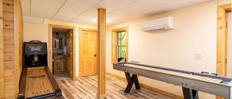 Una habitación con mesa de billar, máquina de billar y suelo de madera.