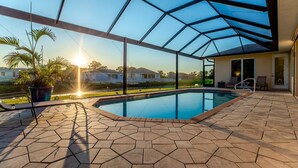 En swimmingpool med ett glastak, omgiven av hexagonformade plattor, och en utsikt över hus i bakgrunden.