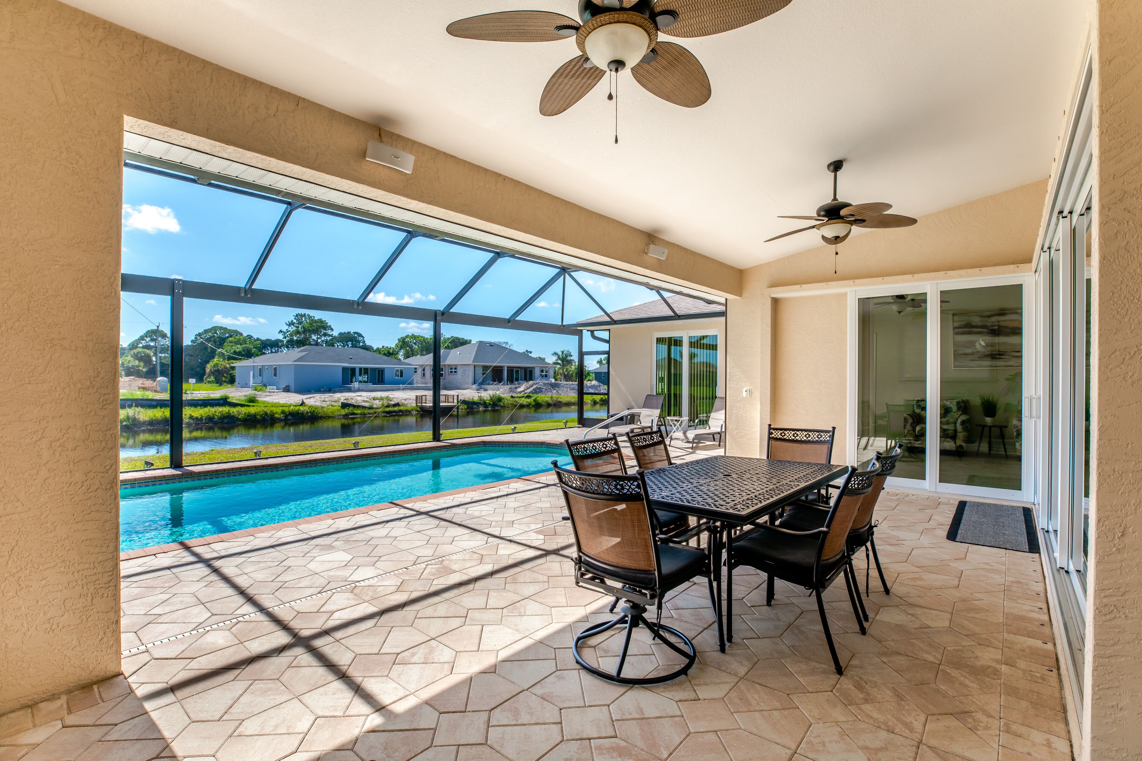 A patio with a pool, outdoor furniture, and a view of a residential area.