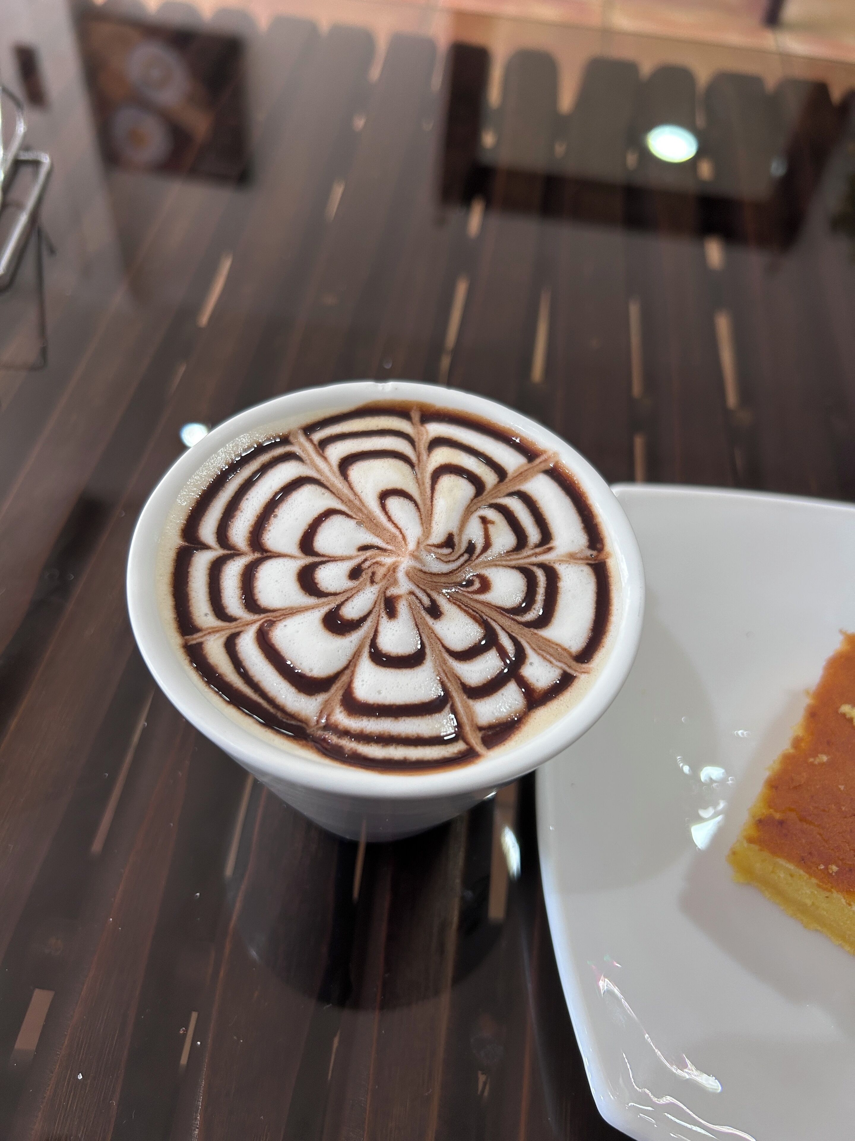 A cup of coffee with intricate latte art on a wooden table.