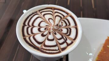 A cup of coffee with intricate latte art on a wooden table.