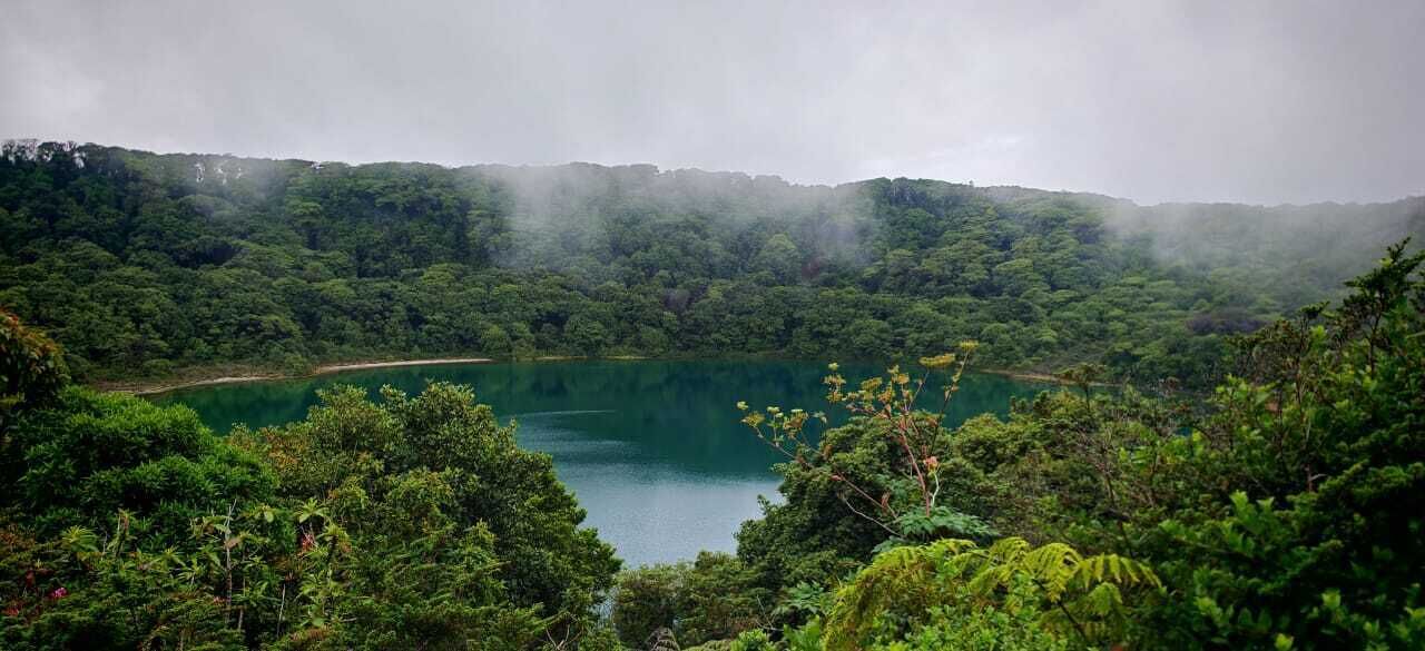Um lago rodeado por uma floresta densa, com vista para as colinas ao redor.