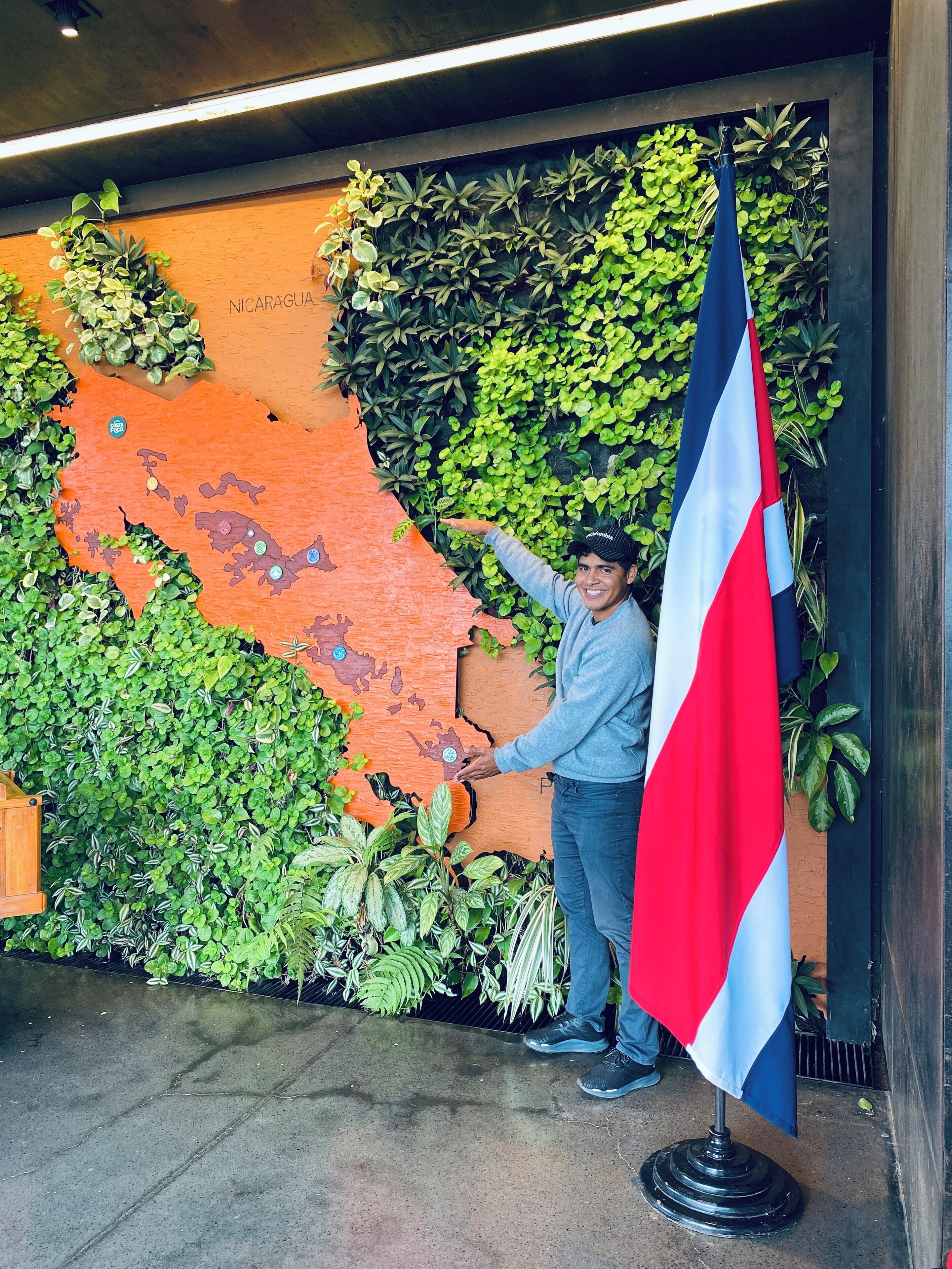 A person standing in front of a wall with a map of Nicaragua and a flag.