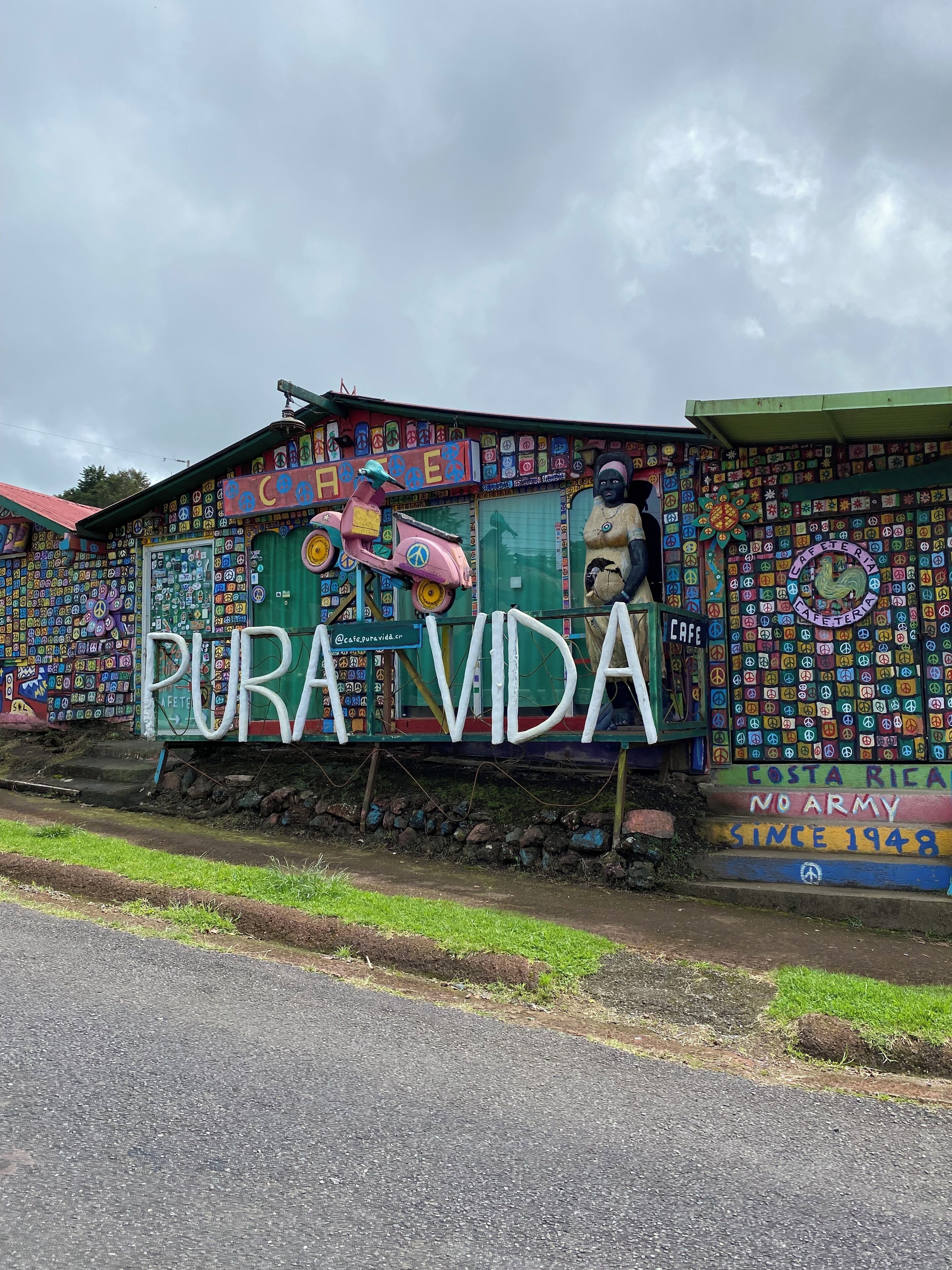 Een kleurrijk gebouw met muurschilderingen en graffiti, inclusief een groot bord met de tekst 'PURA VIDA'.