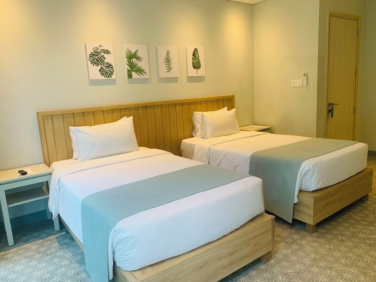 A hotel room with two beds, a nightstand, and wall art.