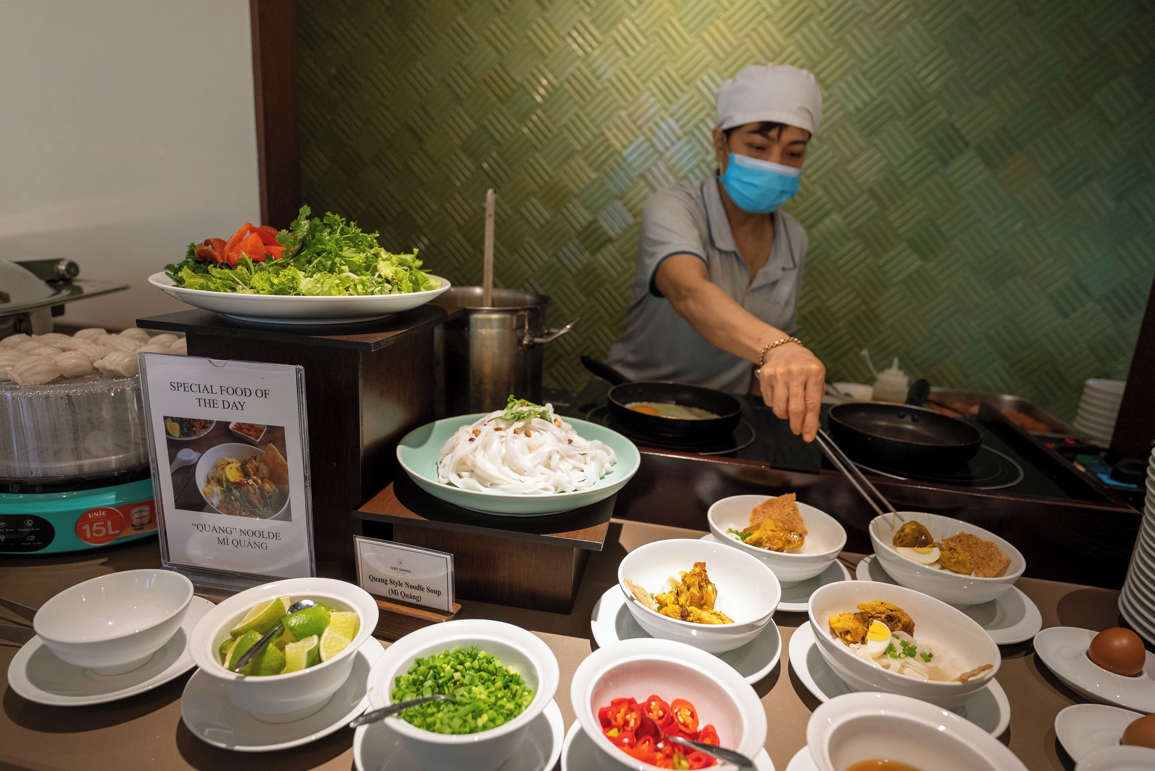 A buffet with various dishes, including a plate of noodles and several bowls of condiments.