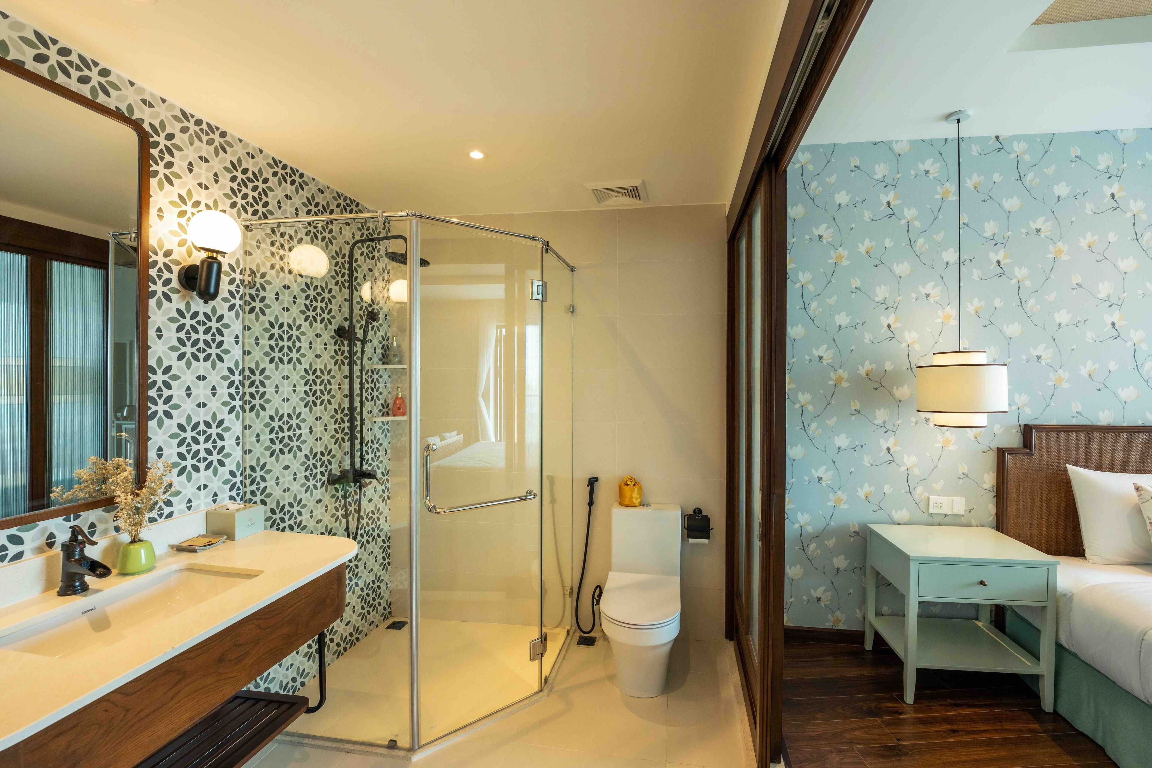 Un baño con cabina de ducha de vidrio, inodoro blanco y lavabo con tocador de madera.