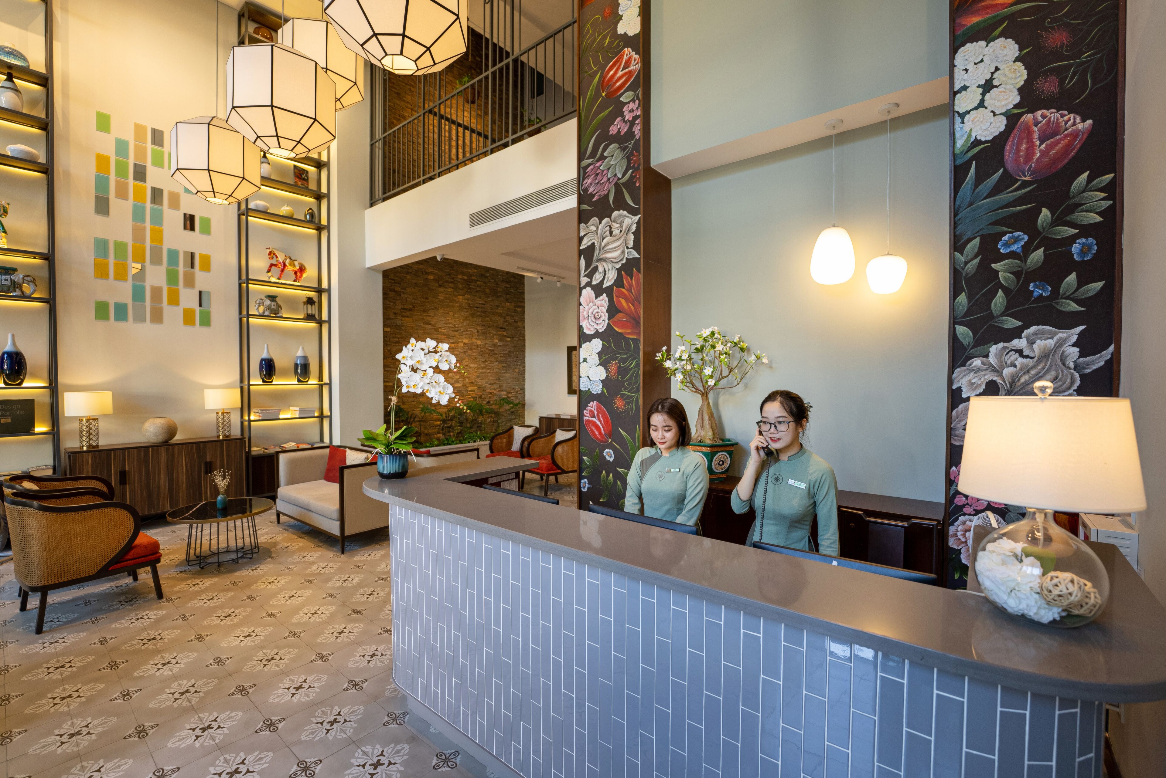 A hotel reception area with a modern design, including a reception desk, seating area, and a staircase.