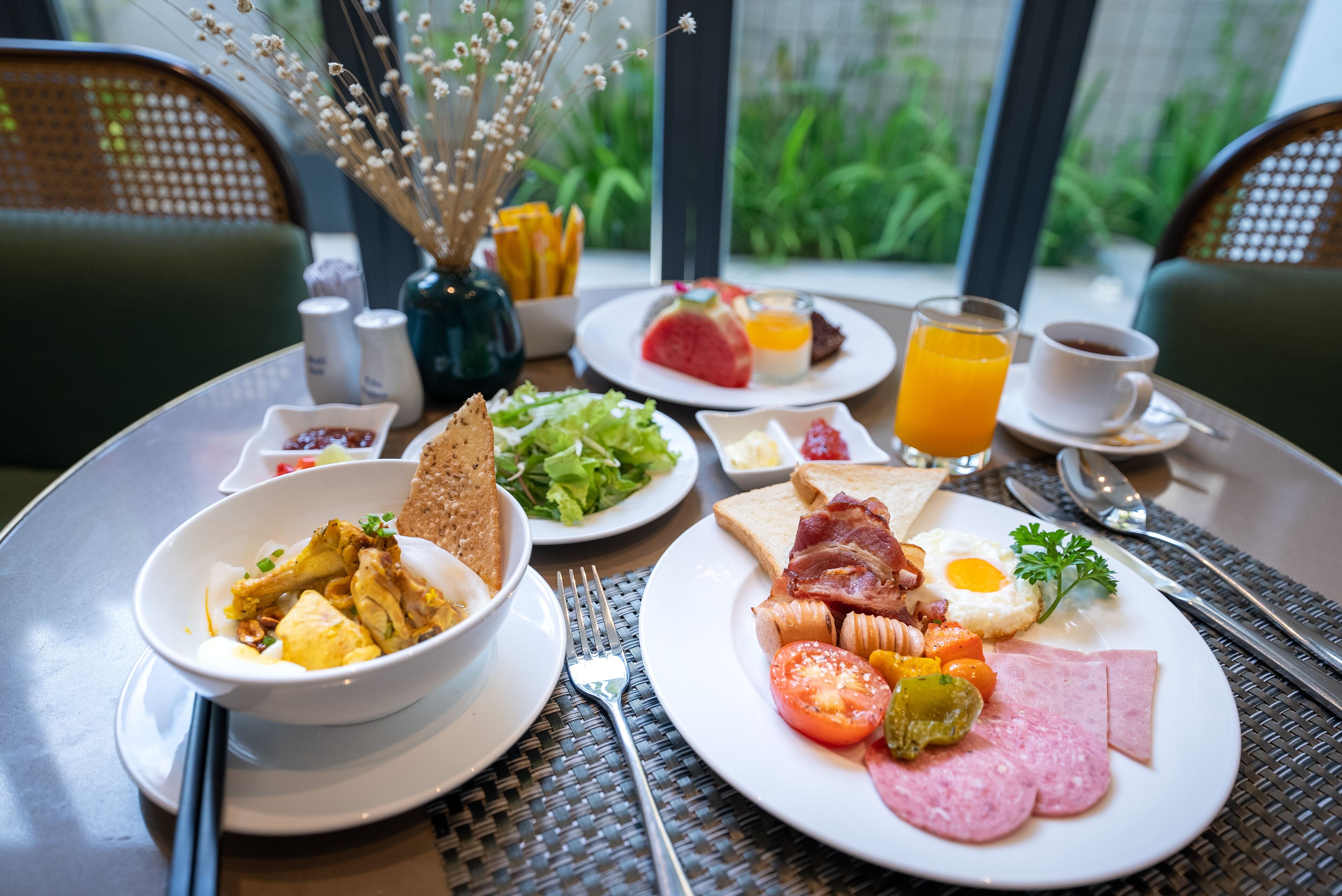 Una mesa de desayuno con platos de comida, un vaso de jugo de naranja y una taza de café.
