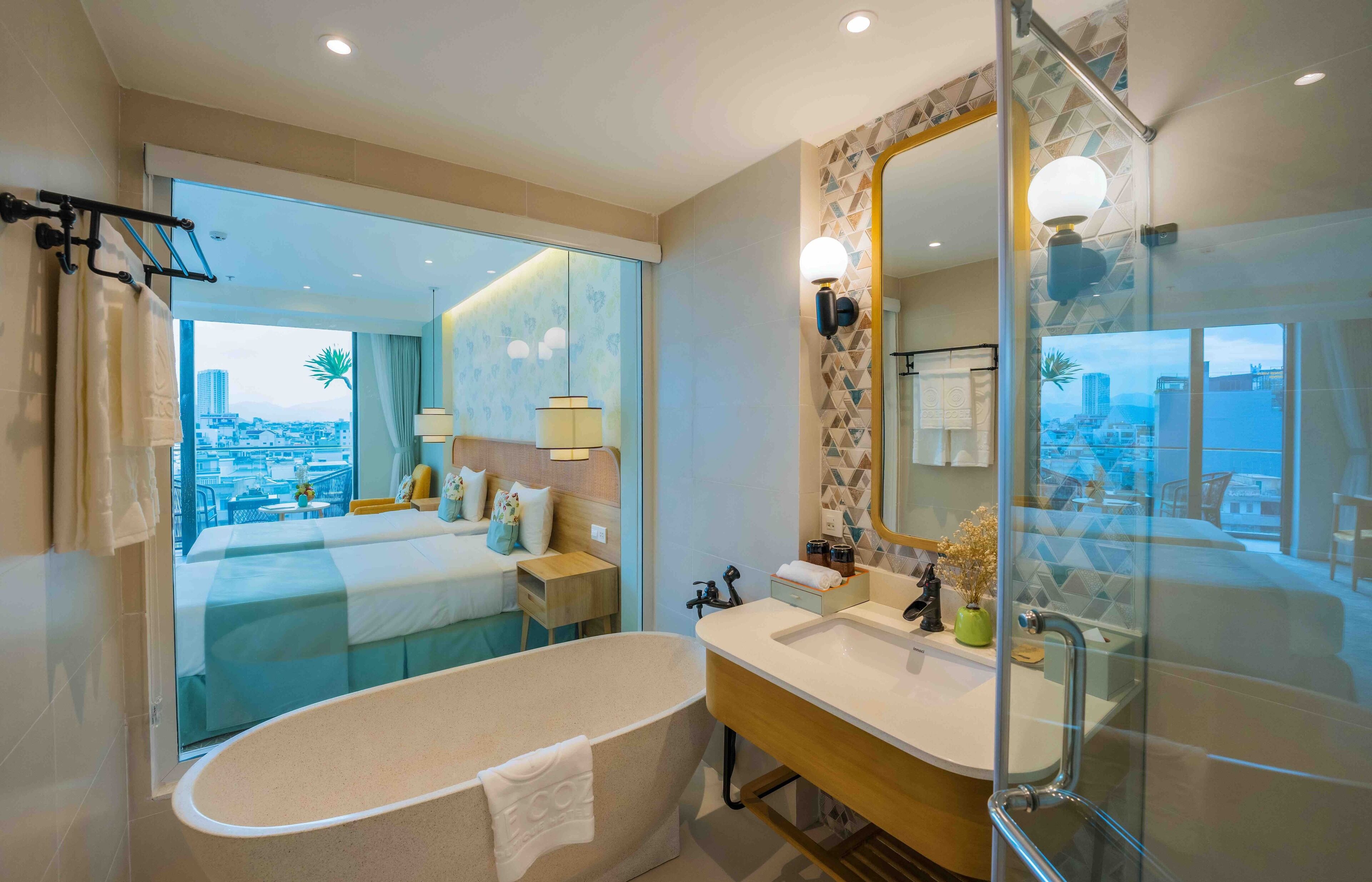 A modern bathroom with a bathtub, a large mirror, and a view of the city.