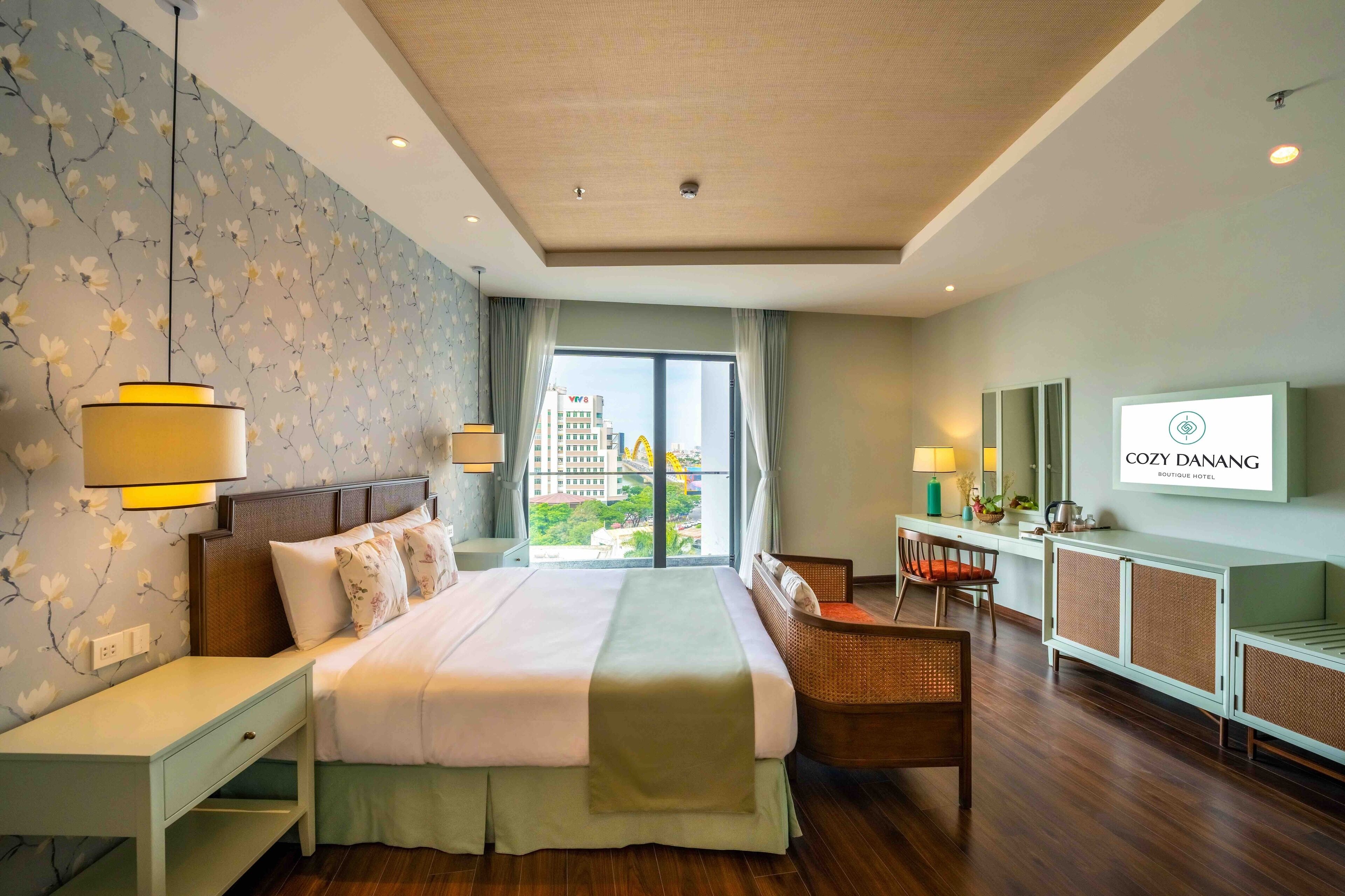 A hotel room with a large bed, bedside tables, a desk, a chair, and a television.