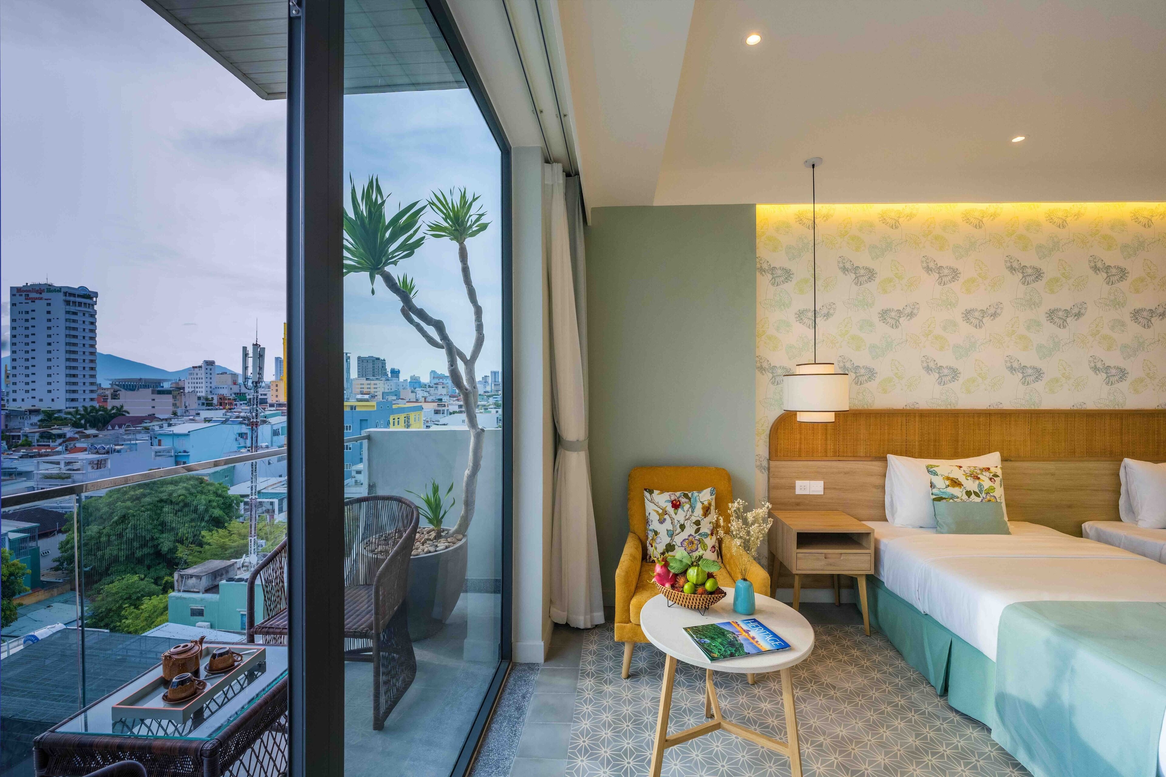 A hotel room with a balcony, a bed, a chair, a table, and a nightstand.
