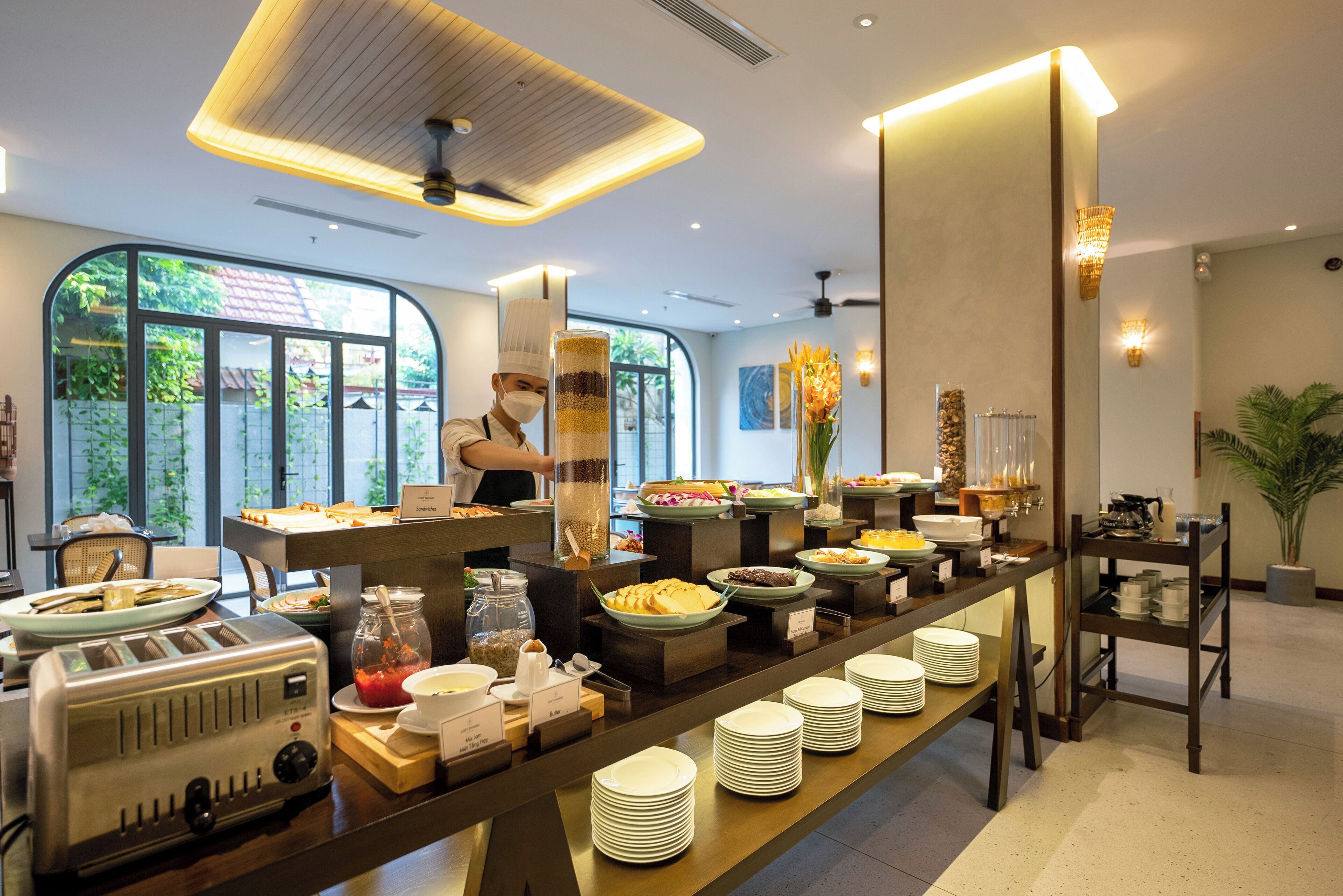 A buffet setup with various food items and a chef preparing food.