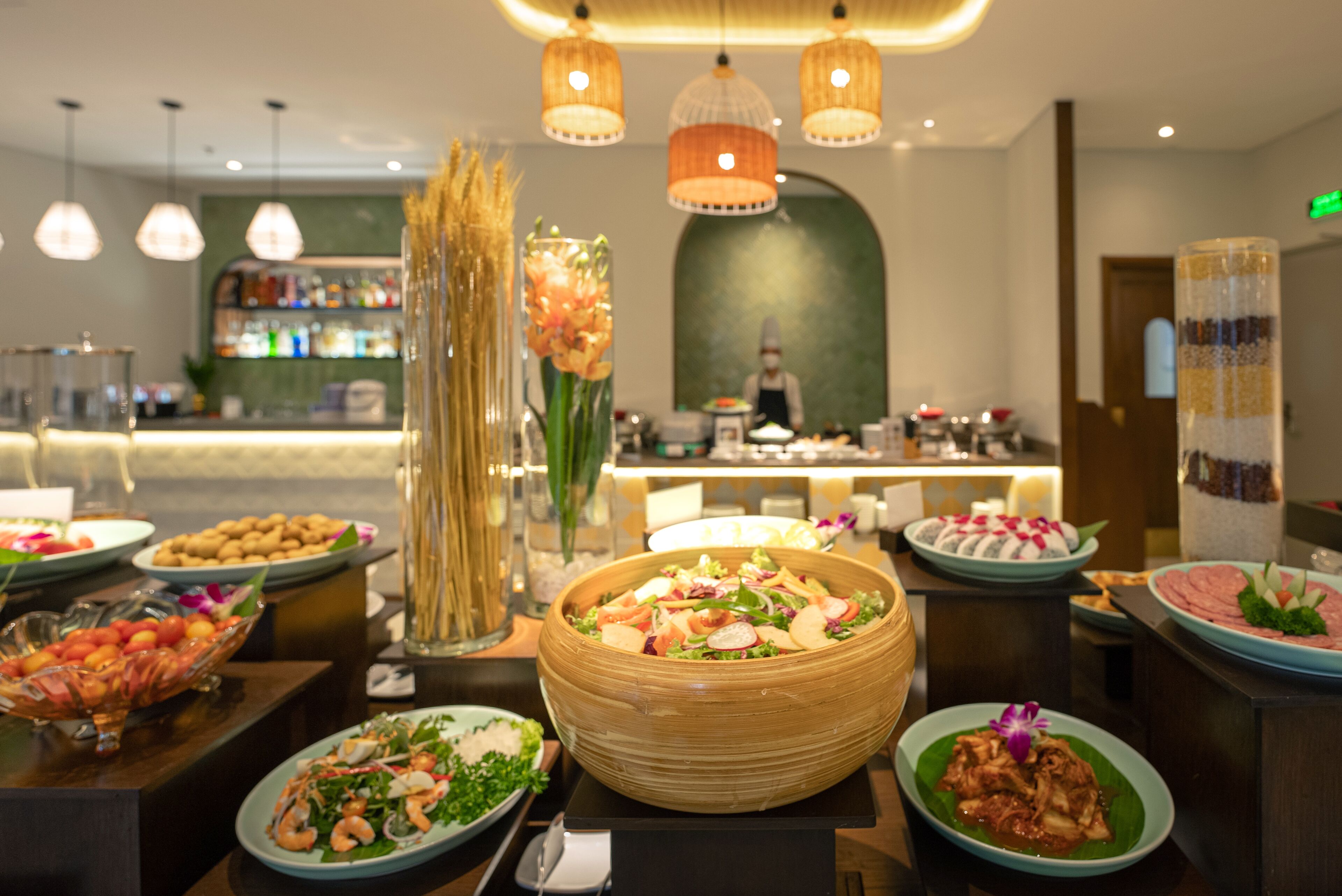 A buffet with various dishes, a bar area, and a chef in the background.