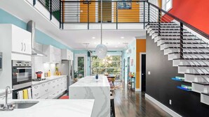 Una cocina moderna con una isla central, una escalera y vistas al exterior.