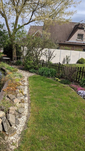 Un jardin bien entretenu, avec une grande variété de plantes et un petit étang.