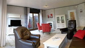 Ein Wohnzimmer mit einer Couch, Sesseln, einem Couchtisch, einem Fernseher und einem Kamin.