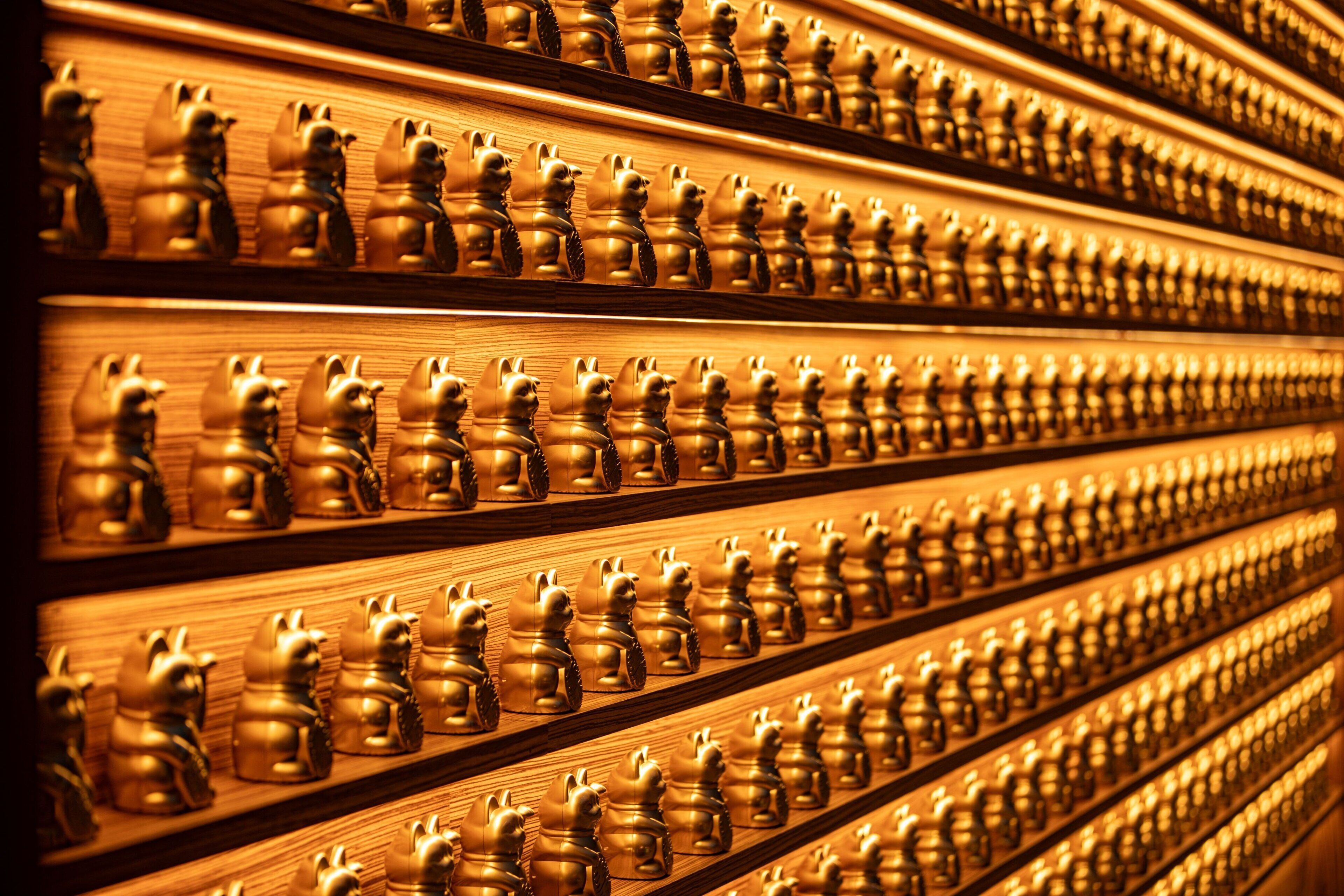 A wall of golden figurines arranged in rows.