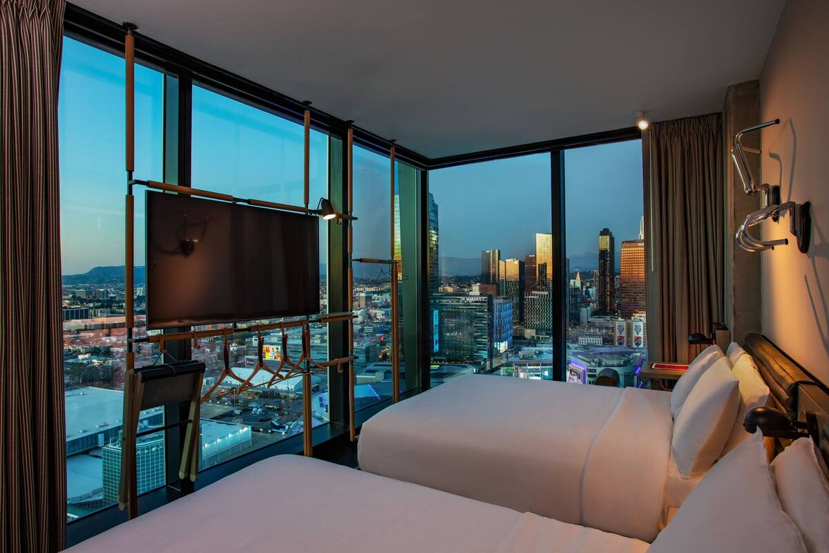 Ein Hotelzimmer mit einem großen Bett, einem Fernseher und Blick auf die Stadt.