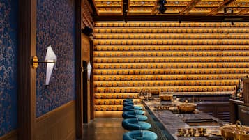 A bar area with a row of blue barstools, a marble countertop, and a wall of trophies.