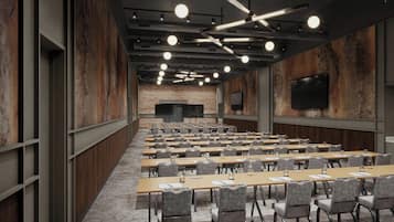Ein Konferenzraum mit Tischen, Stühlen und einer großen Leinwand, im Hintergrund eine Ziegelwand.