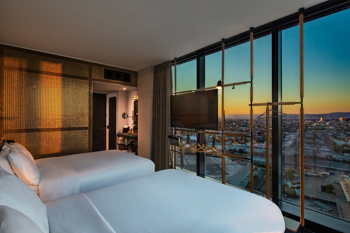 Habitación de hotel con una cama grande, televisión y vistas a la ciudad.