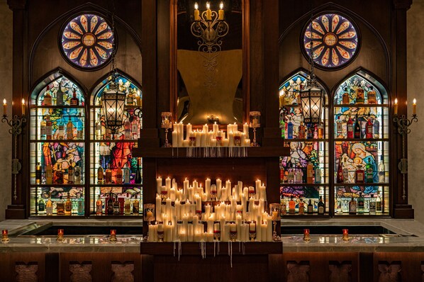 Una zona de bar con múltiples velas y una exhibición de botellas de licor.