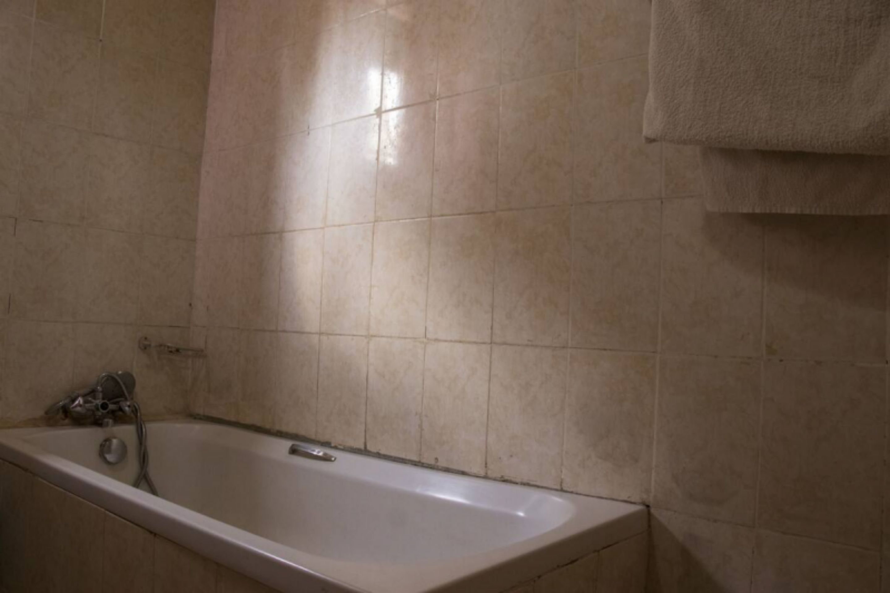 A bathroom with a bathtub, tiled walls, and a towel hanging on the wall.