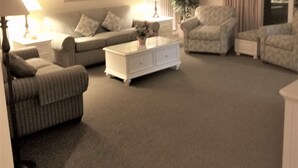 Una sala de estar con sofá, sillones, una mesa de centro y una lámpara.