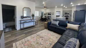 A modern living room with a dark leather sofa, a patterned rug, and a dining area with a table and chairs. - Perfect family friendly Home Base for your Red Rock adventures (Kanab)