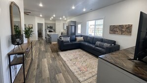 A modern living room with a sectional sofa, a dining area, and a kitchen. - Perfect family friendly Home Base for your Red Rock adventures (Kanab)
