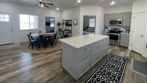 A modern kitchen with a central island, built-in appliances, and a dining area with a round table and chairs. - Perfect family friendly Home Base for your Red Rock adventures (Kanab)
