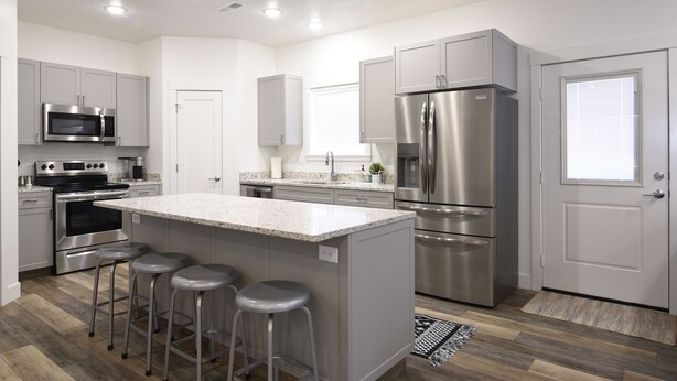 A modern kitchen with stainless steel appliances, a central island with stools, and a hardwood floor. - Perfect family friendly Home Base for your Red Rock adventures (Kanab)