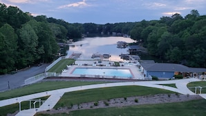 Un complejo turístico junto al lago con piscina, embarcaciones amarradas y zona de estacionamiento.