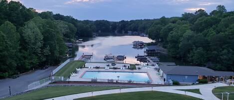 A lakeside resort with a swimming pool, docked boats, and a parking area.