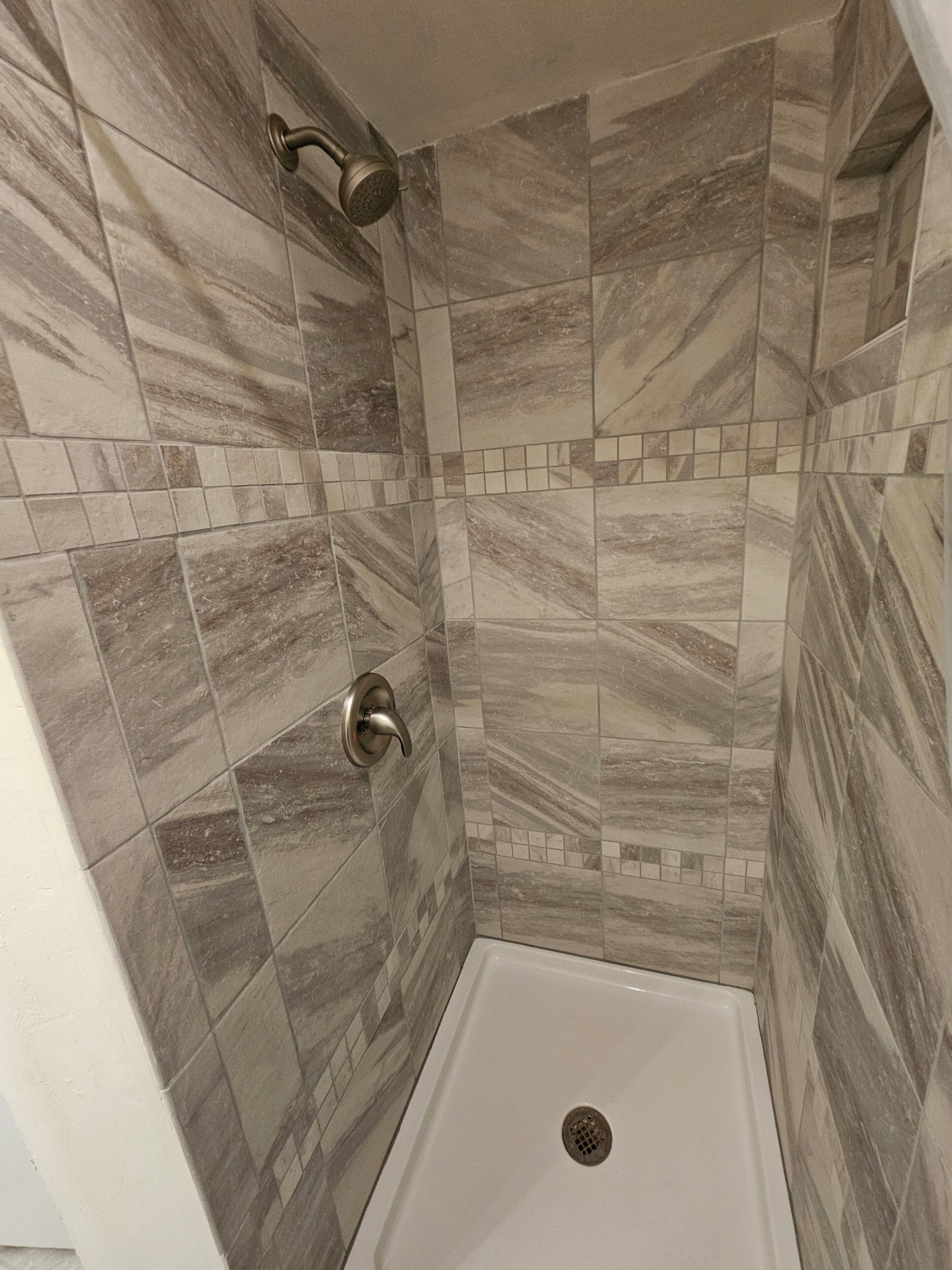 Eine Dusche mit Handbrause und Armaturen an der Wand.