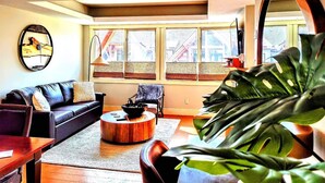 A living room with a sofa, armchair, coffee table, and large windows. - Rundle Rock Retreat | Majestic Views - Luxury Condo (Canmore)