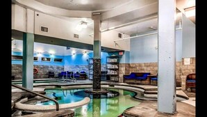 A spa area with a central hot tub, seating areas, and a reception desk. - Rundle Rock Retreat | Majestic Views - Luxury Condo (Canmore)