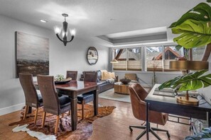 A spacious living area with a dining table, chairs, a sofa, and a large plant.