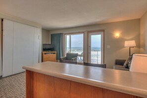 A hotel room with a kitchenette, a television, a seating area with a view of the sea, and a balcony. - Oceanfront One Bedroom Suite, Stunning Views & King Bed! (Lincoln City)